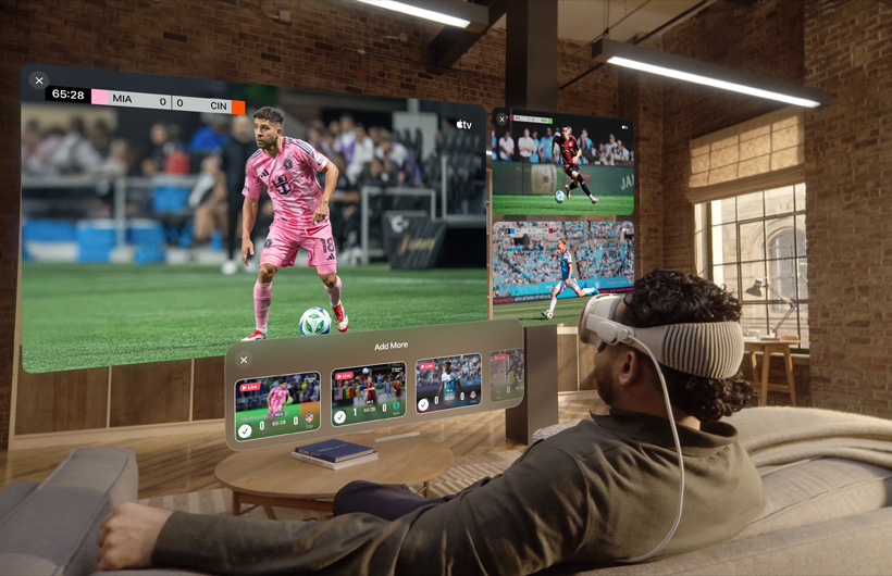 一個人戴著 Apple Vision Pro 坐在客廳的沙發上，在他面前顯示的是一個大型的影片螢幕，一旁有兩個較小的螢幕，各別顯示不同的體育賽事。大螢幕下方有一個選項視窗顯示：加入更多選項