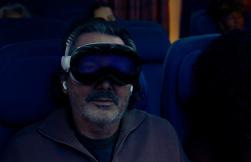 飛行機の座席に座り、デュアルニットバンドを取りつけたApple Vision Proを装着している人物