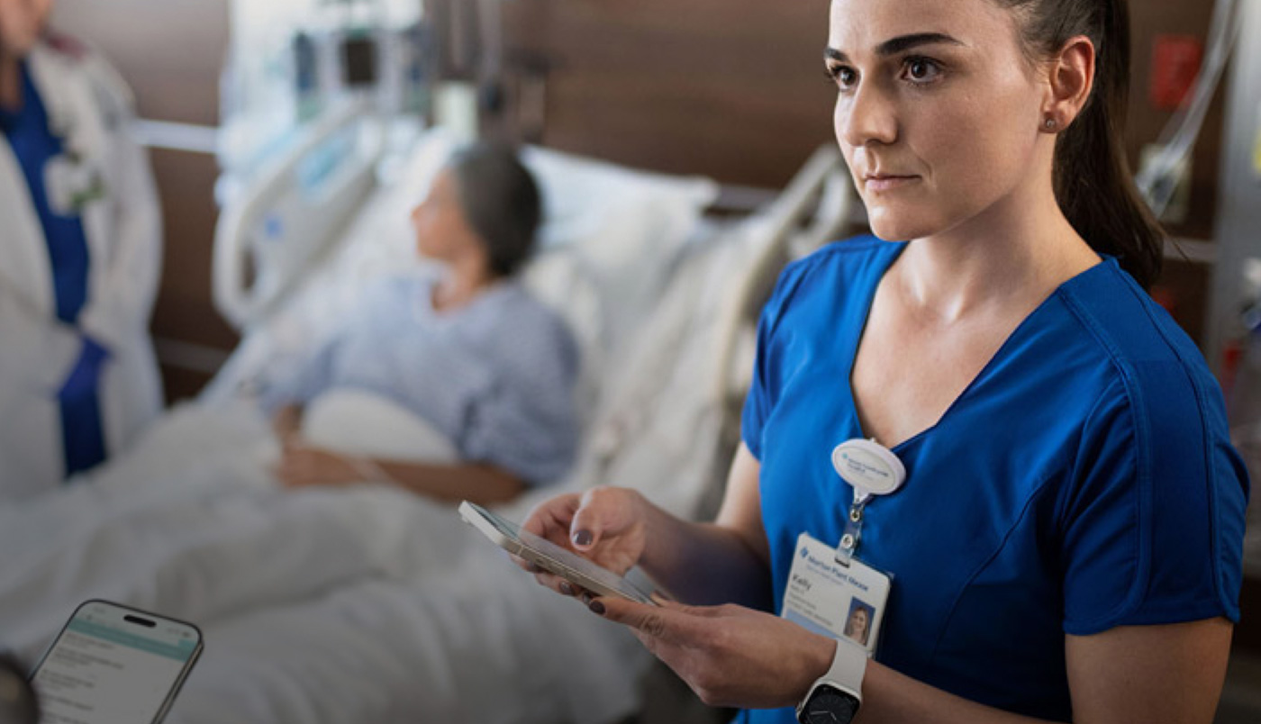 En sygeplejerske skriver på sin iPhone, mens en læge taler med en patient.