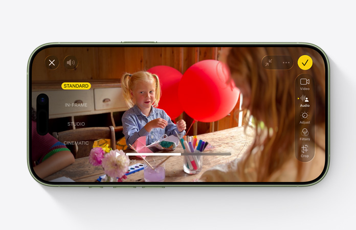 Vista frontal do iPhone 17, vídeo com a funcionalidade Mistura de áudio em utilização e criança à mesa a brincar com balões